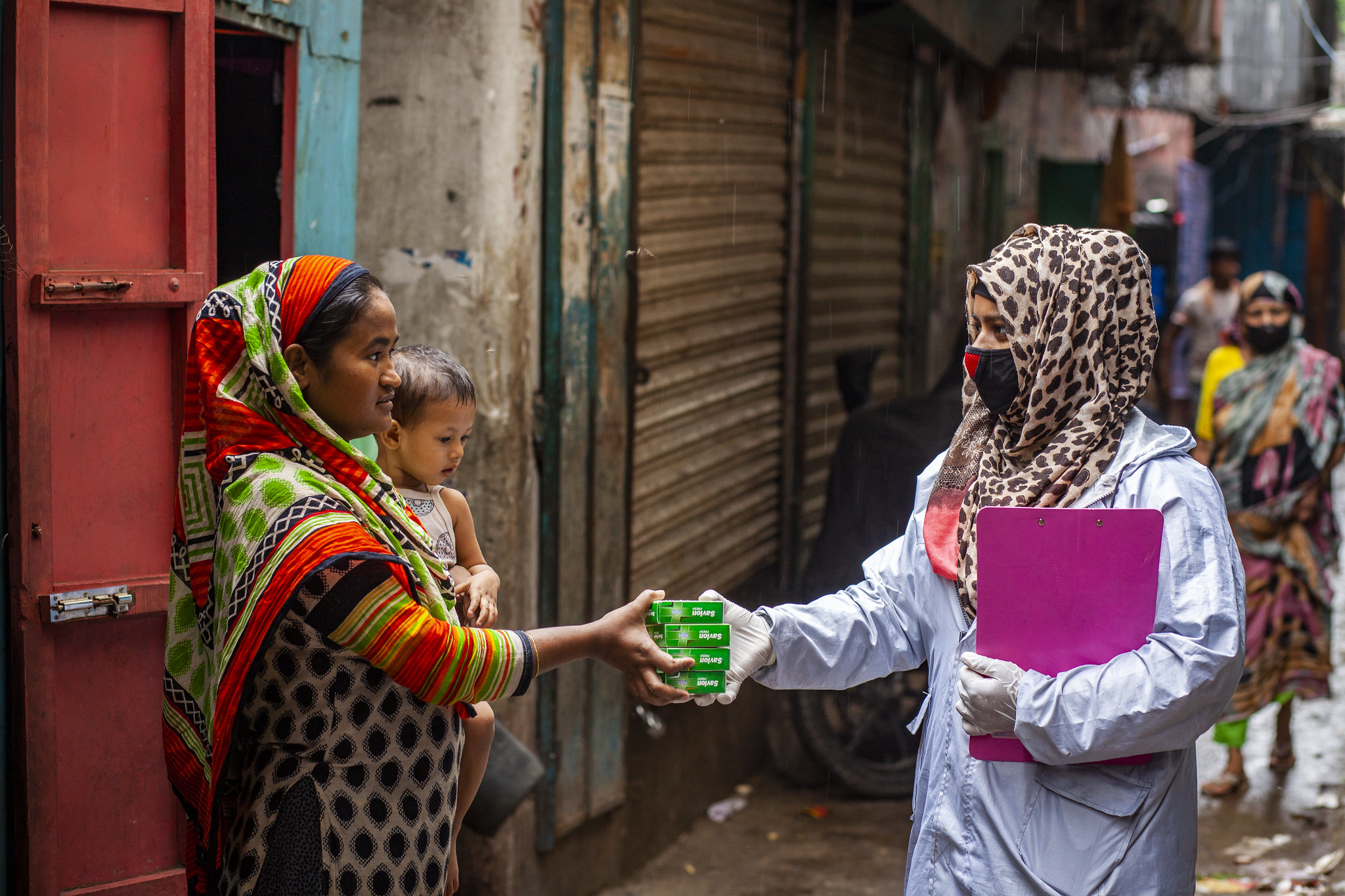 A community facilitator distributes anti-bacterial and disinfecting soap to a family in Dhaka.
